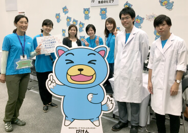 「青少年のための科学の祭典大阪大会2018サイエンスフェスタ」出展時のBIKEN職員とびけんの立て看板の集合写真
